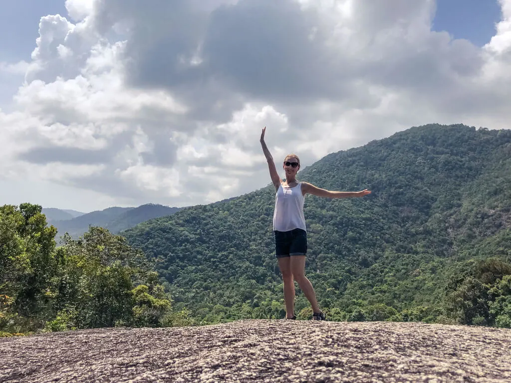 Posing on a large rock with green hills behind