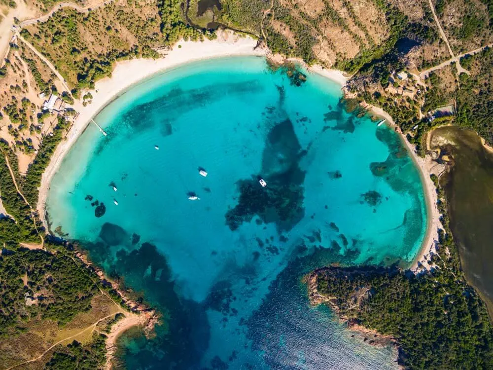 Aerial photo of a moon-shaped white-sand beach in Corsica France