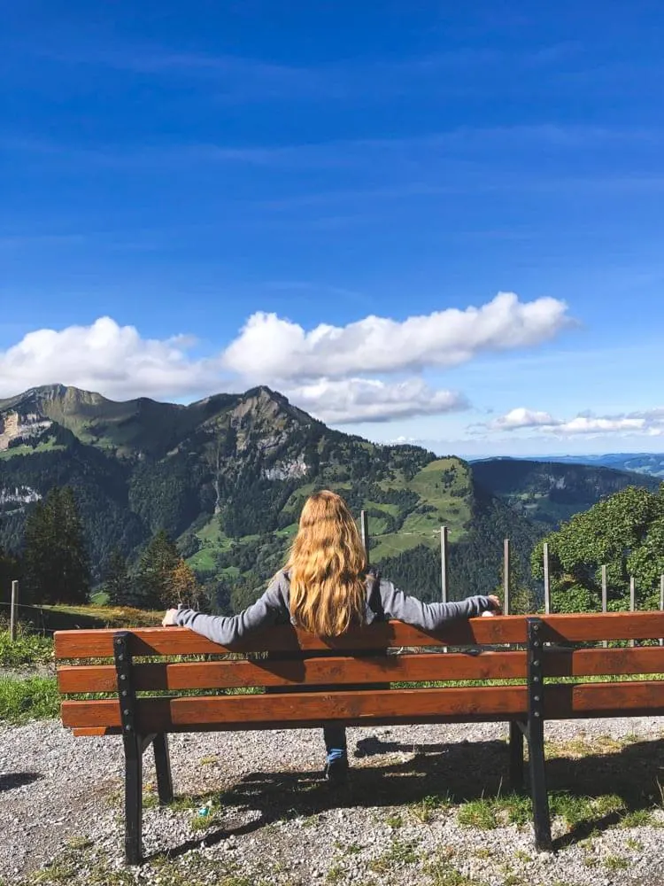 Veronika from Travel Geekery sitting on a bench in the Alps