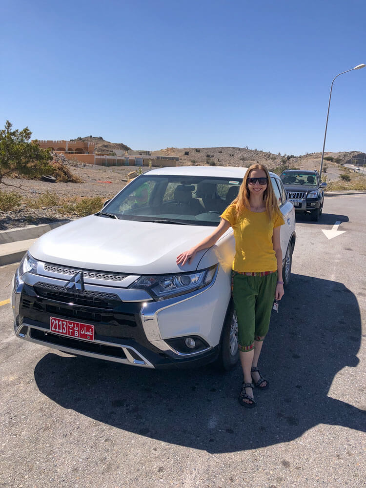 Veronika posing with her rented car in Oman