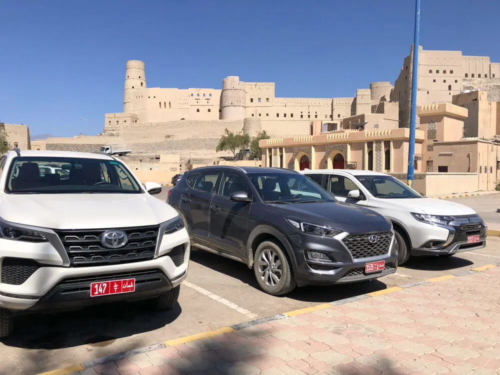 Cars parked in front of a fortress in Oman
