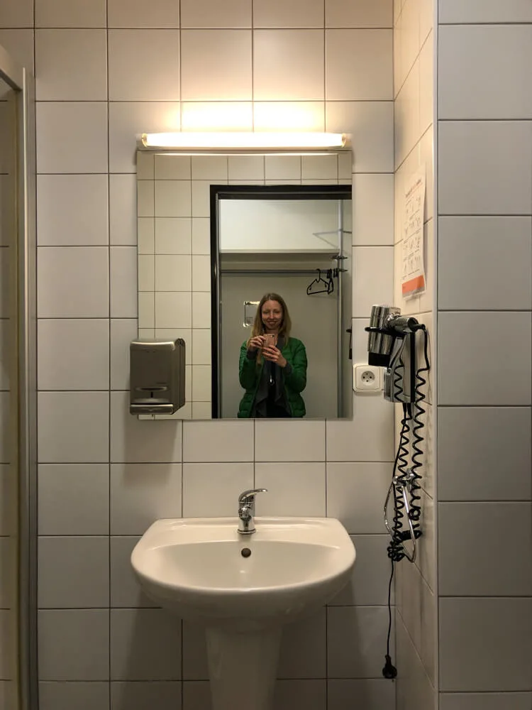 Umyvadlo a zrcadlo v koupelně hotelového pokoje na letišti Praha