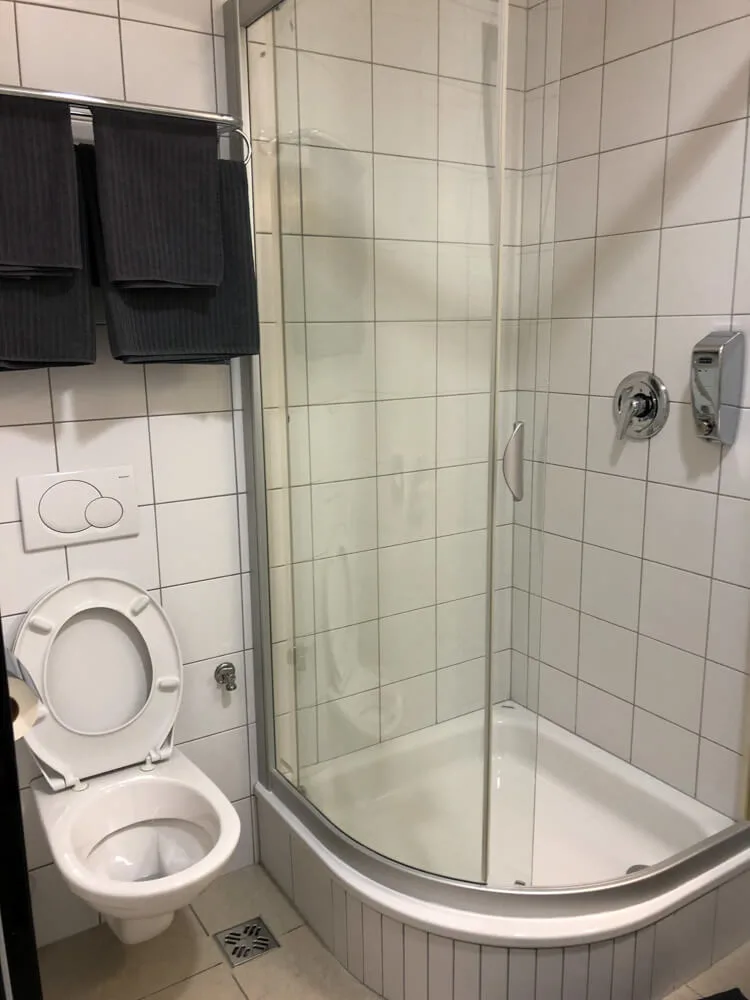 Pohled na sprchový kout a toaletu hotelového pokoje na letišti Praha