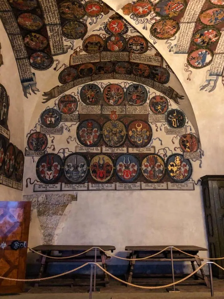 A historical room with walls covered in coats of arms.