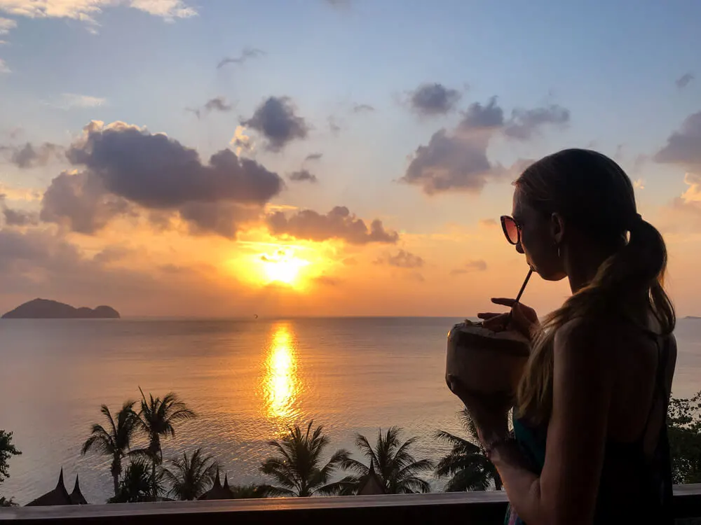 Veronika sipping on a fresh coconut and watching the sunset in Thailand