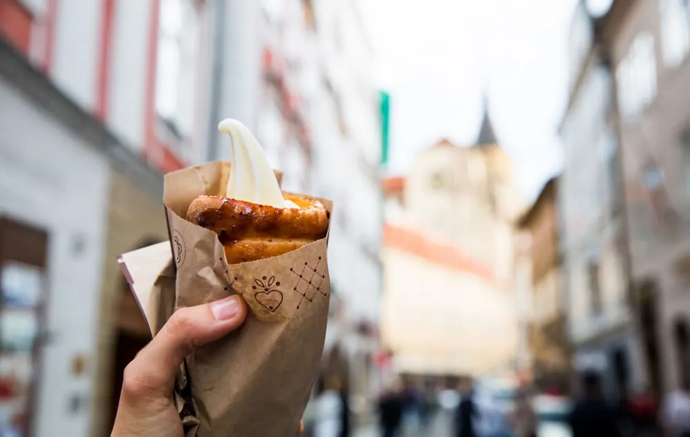 A hand holding a cinnamon chimney cake