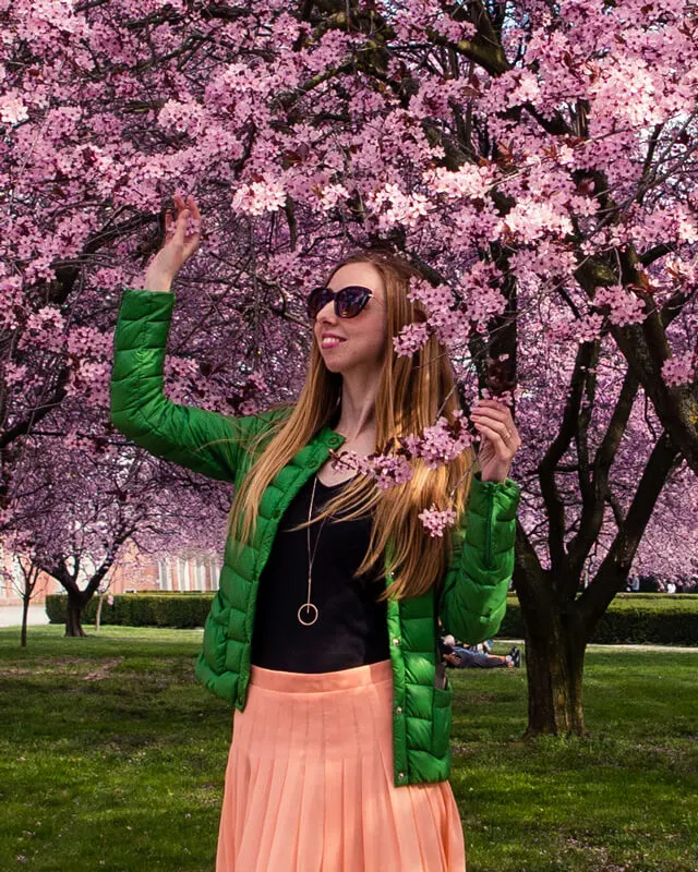 Veronika wearing a puffer travel jacket among blossoming cherry trees