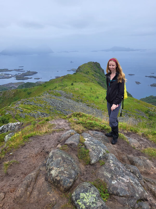 Veronika in a lightweight travel jacket posing on a cliff in Norway