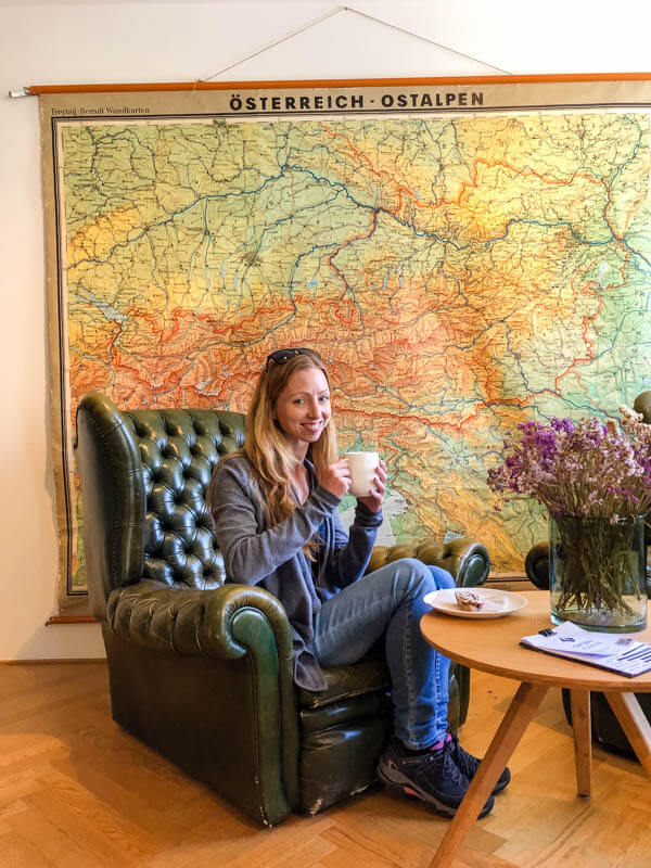 Veronika of TravelGeekery sitting in an armchair holding a mug with both hands