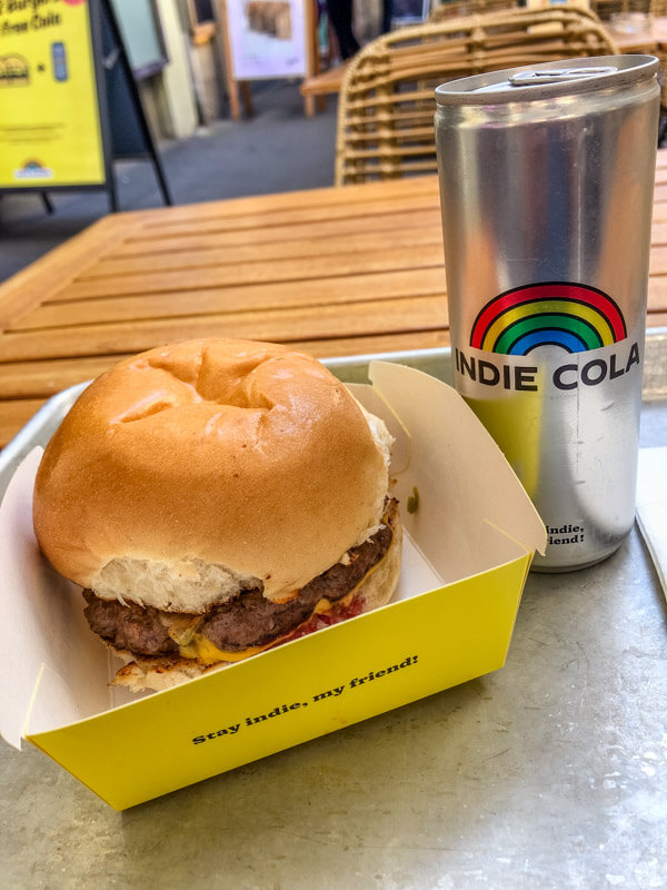 A closeup of a burger and a cola can