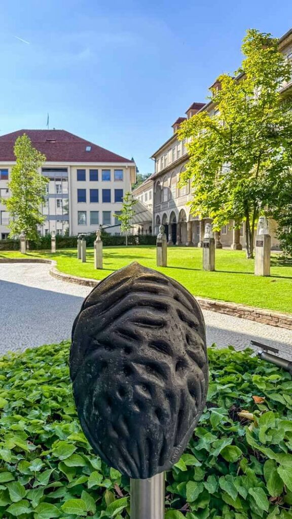 A metal sculpture of a peach pit with a view of government buildings in Graz