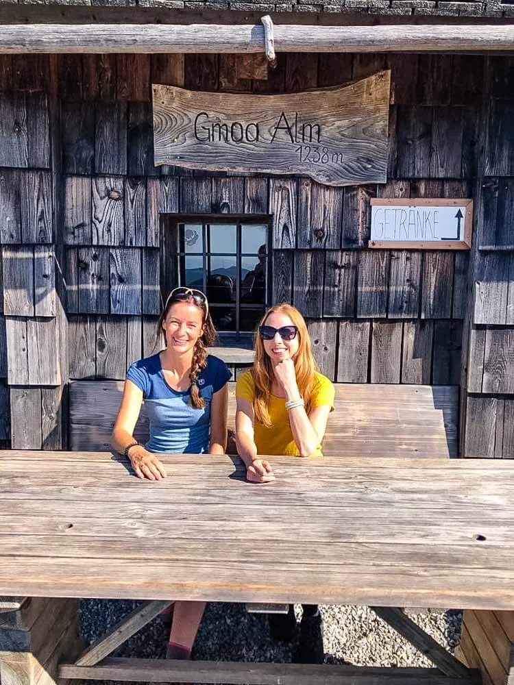 Two girls enjoying the sunshine outside of a mountain hut