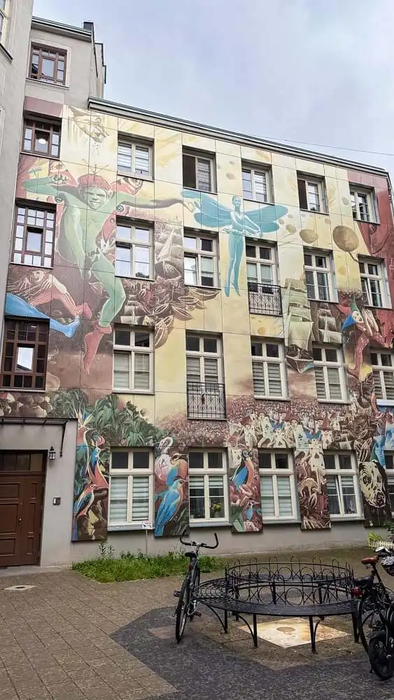 A view of a courtyard with a building covered in a large mural