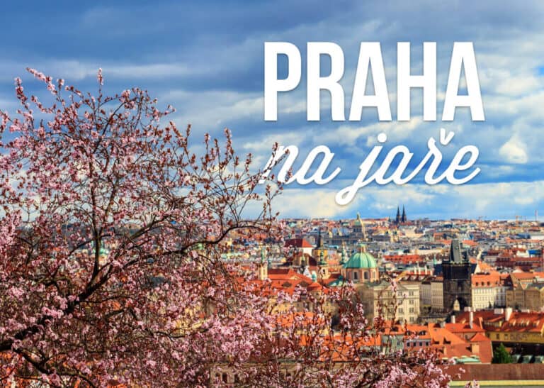 Kvetoucí třešňové stromy s panoramatickým výhledem na historické střechy, kostelní věže a památky Prahy pod modrou oblohou s mraky. Text "PRAHA na jaře" zdůrazňuje krásu jarní sezóny.
