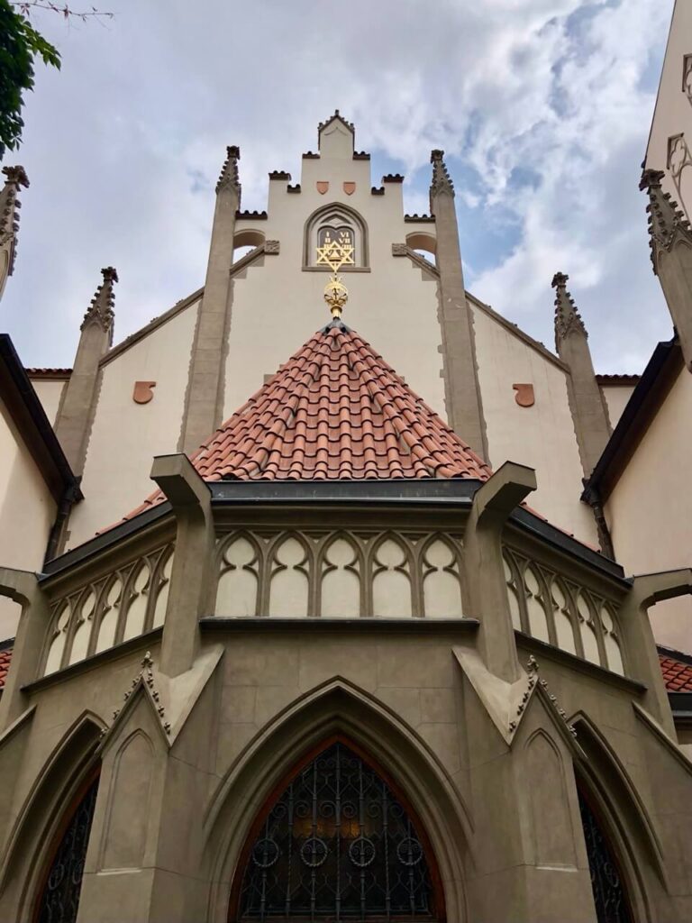 Exterior of the Spanish Synagogue in Prague with pointed Gothic elements and a gold Star of David above the entrance.