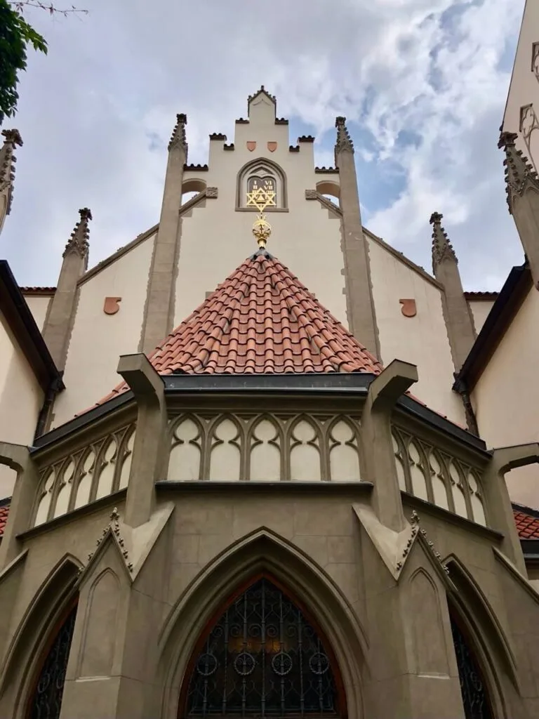 Exterior of the Spanish Synagogue in Prague with pointed Gothic elements and a gold Star of David above the entrance.