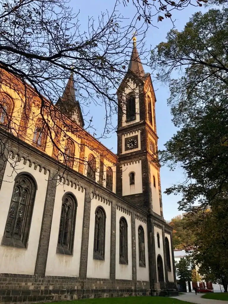 Neo-Romanesque Church of St. Cyril and Methodius in Prague with tall twin spires and arched windows lit by the setting sun.