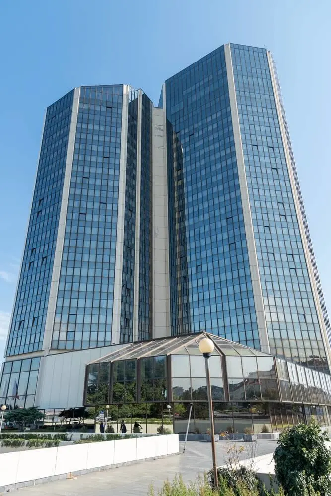 Tall, modern skyscraper with a glass-paneled facade and angular design, featuring a lower glass atrium at its base in Prague.