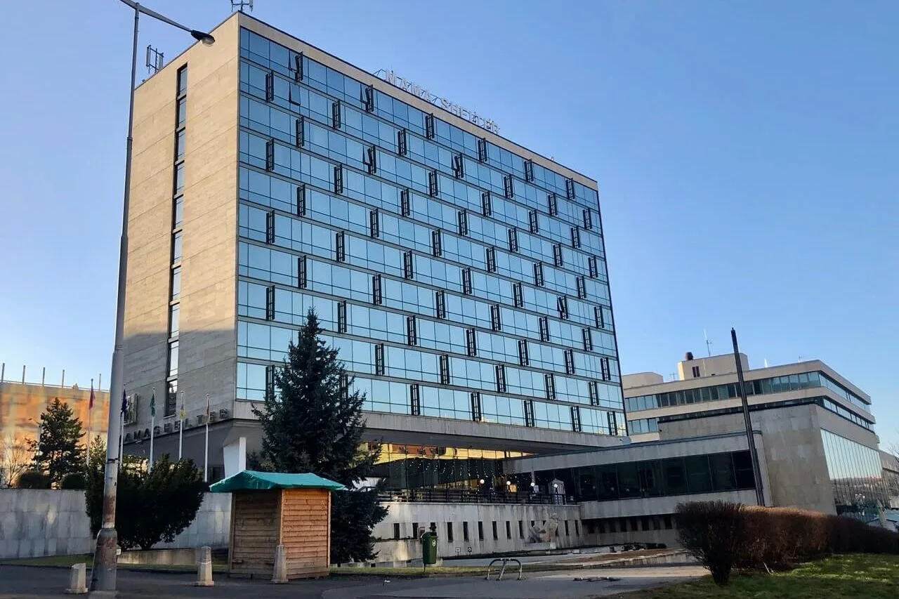 Exterior shot of Mama Shelter Prague taken from a distance, showing the full height of the modern glass building under clear skies.