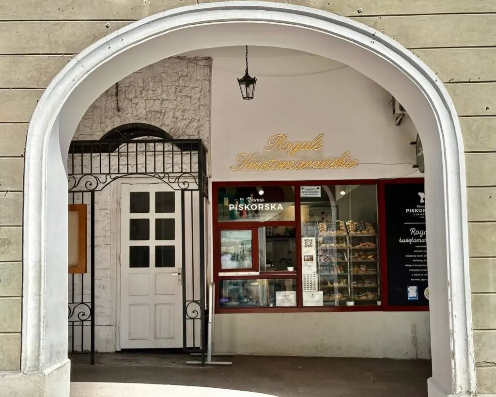A bakery window labeled “Rogale Świętomarcińskie” displays trays of crescent-shaped pastries.
