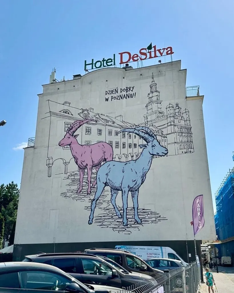 Large mural of two colorful goats and the words “Dzień dobry w Poznaniu!” on the side of Hotel DeSilva.