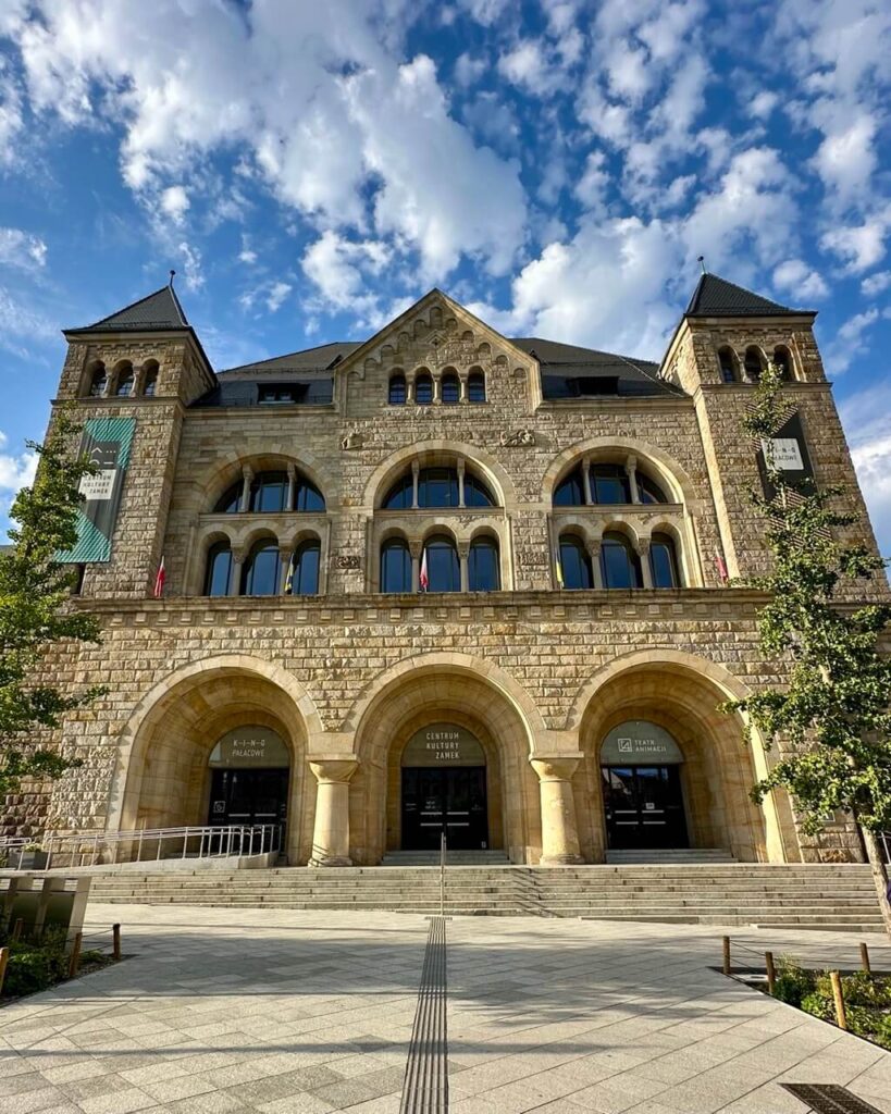 Grand facade of the Imperial Castle in Poznan with arched entrances and Romanesque stone architecture.