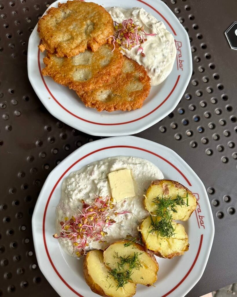 Overhead view of two plates, one with fried potato pancakes and the other with baked potatoes and cottage cheese.
