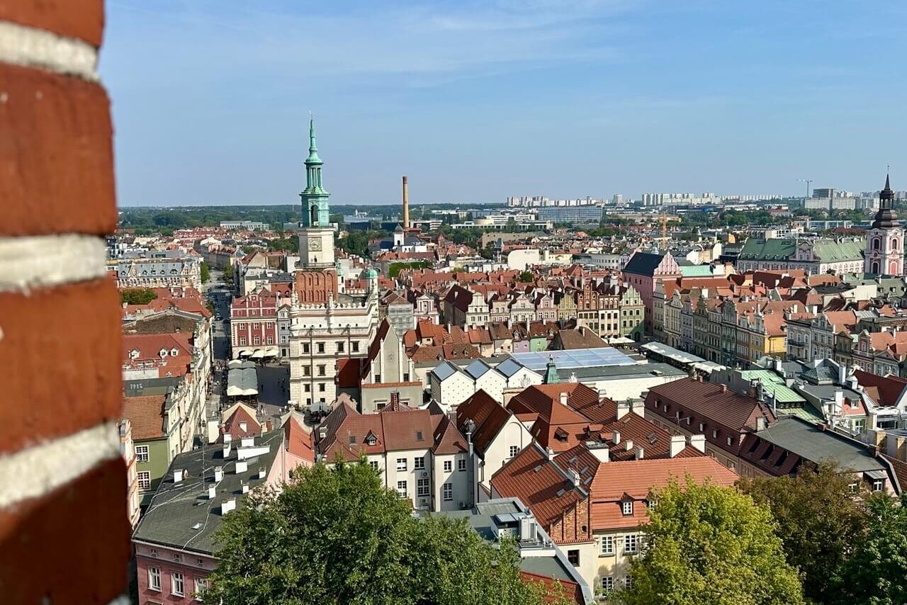 Aerial view of Poznan Old Town with red rooftops, church towers, and historic buildings stretching toward the horizon.
