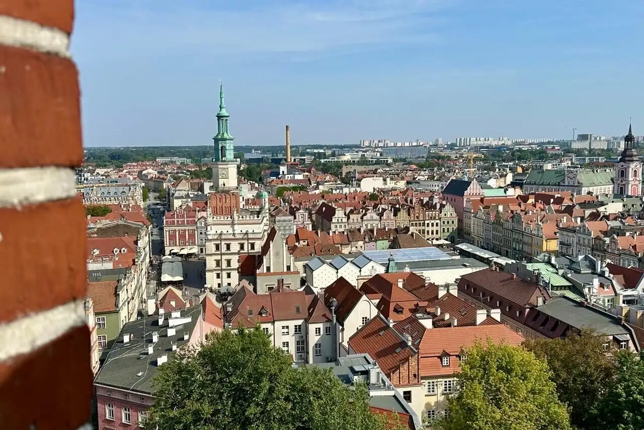 Aerial view of Poznan Old Town with red rooftops, church towers, and historic buildings stretching toward the horizon.