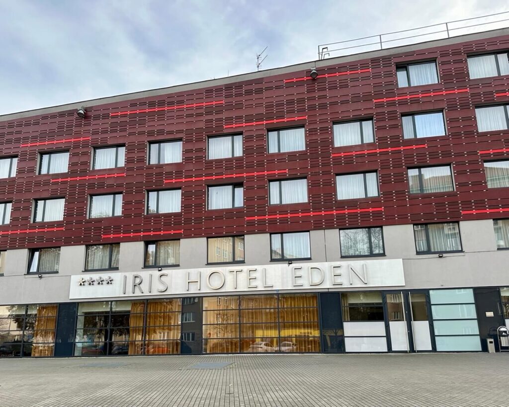 Iris Hotel Eden Prague with red and gray modern exterior and large hotel sign on the facade.